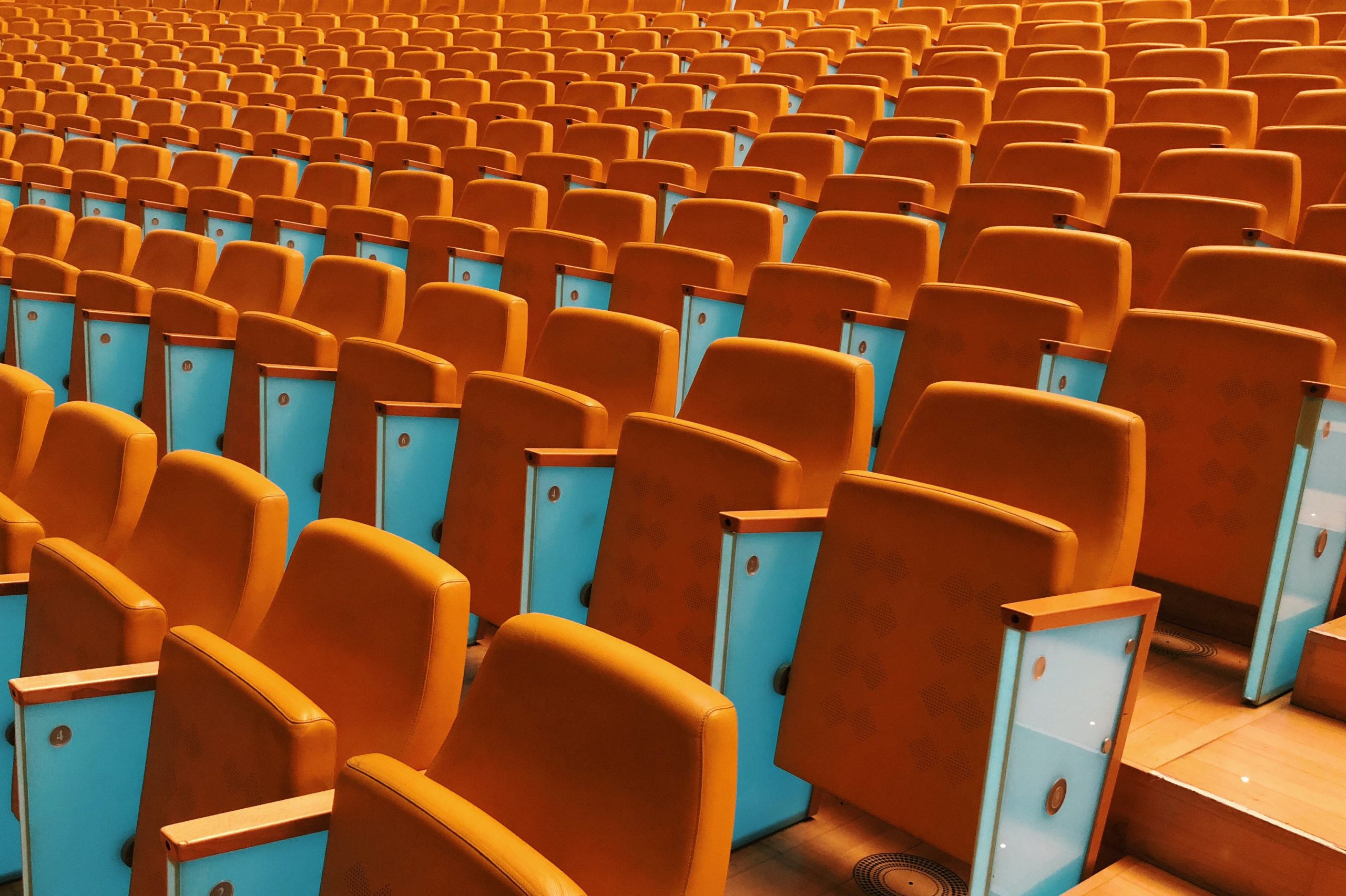 an empty auditorium with rows of orange chairs